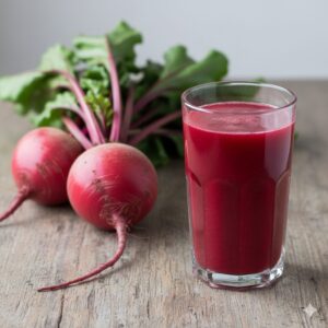 Image 3 - Vibrant red beetroots on a wooden cutting board next to a glass of fresh ABC juice.