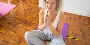 An elderly person practicing gentle chair yoga in a bright, peaceful living room.