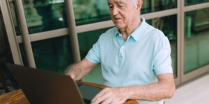 A senior person working securely on a laptop in a well-lit home office.