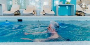 A senior person enjoying a gentle aquatic therapy session in a warm, accessible indoor pool.