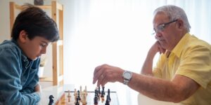 A warm, intergenerational scene of a board game being played on a wooden table.