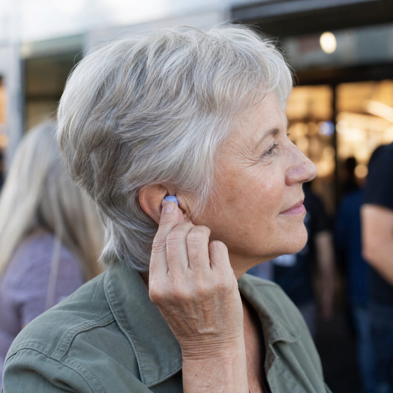 Older concertgoer fitting a reusable earplug
