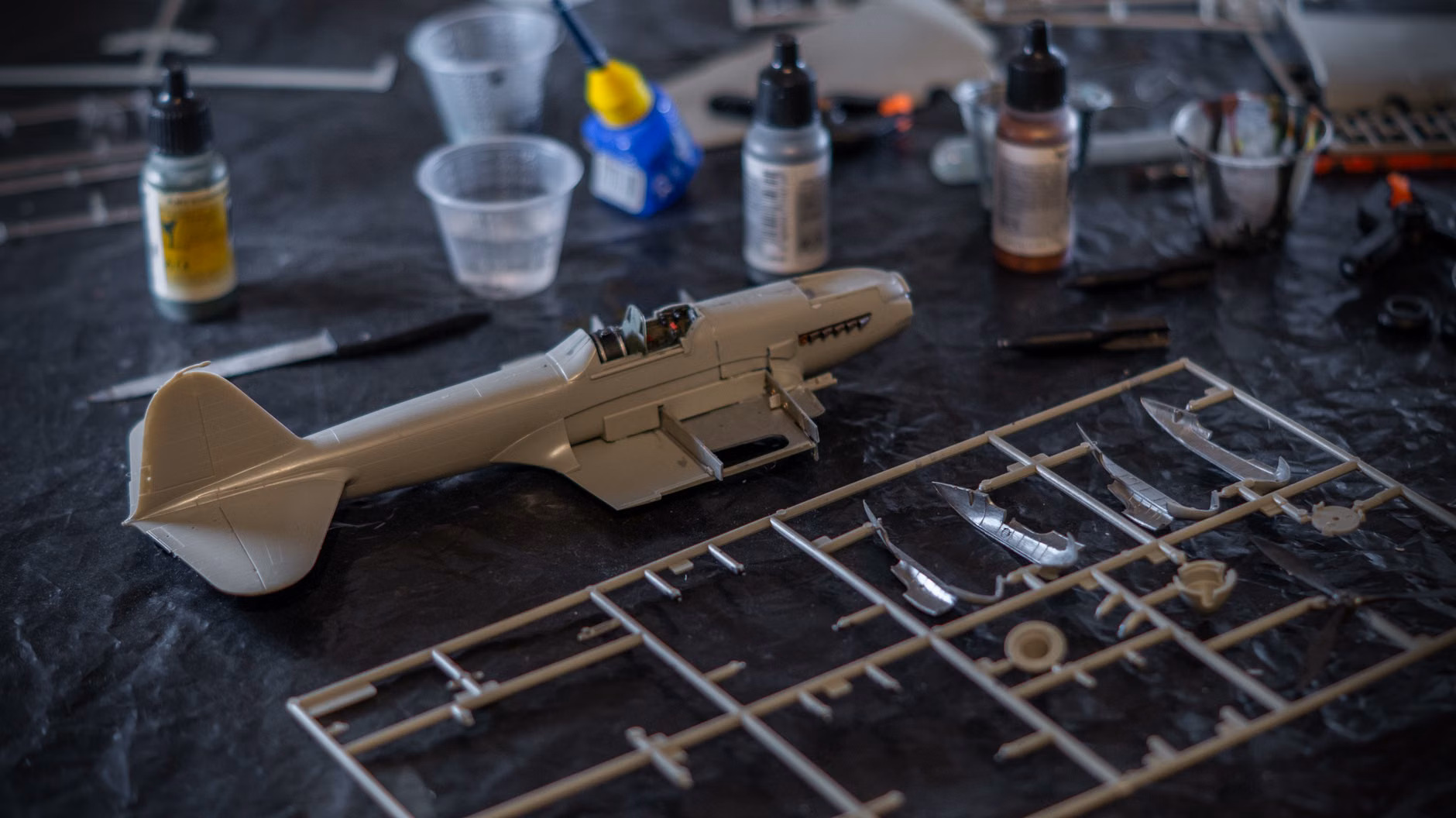 An organized hobby workbench with tools and model parts.