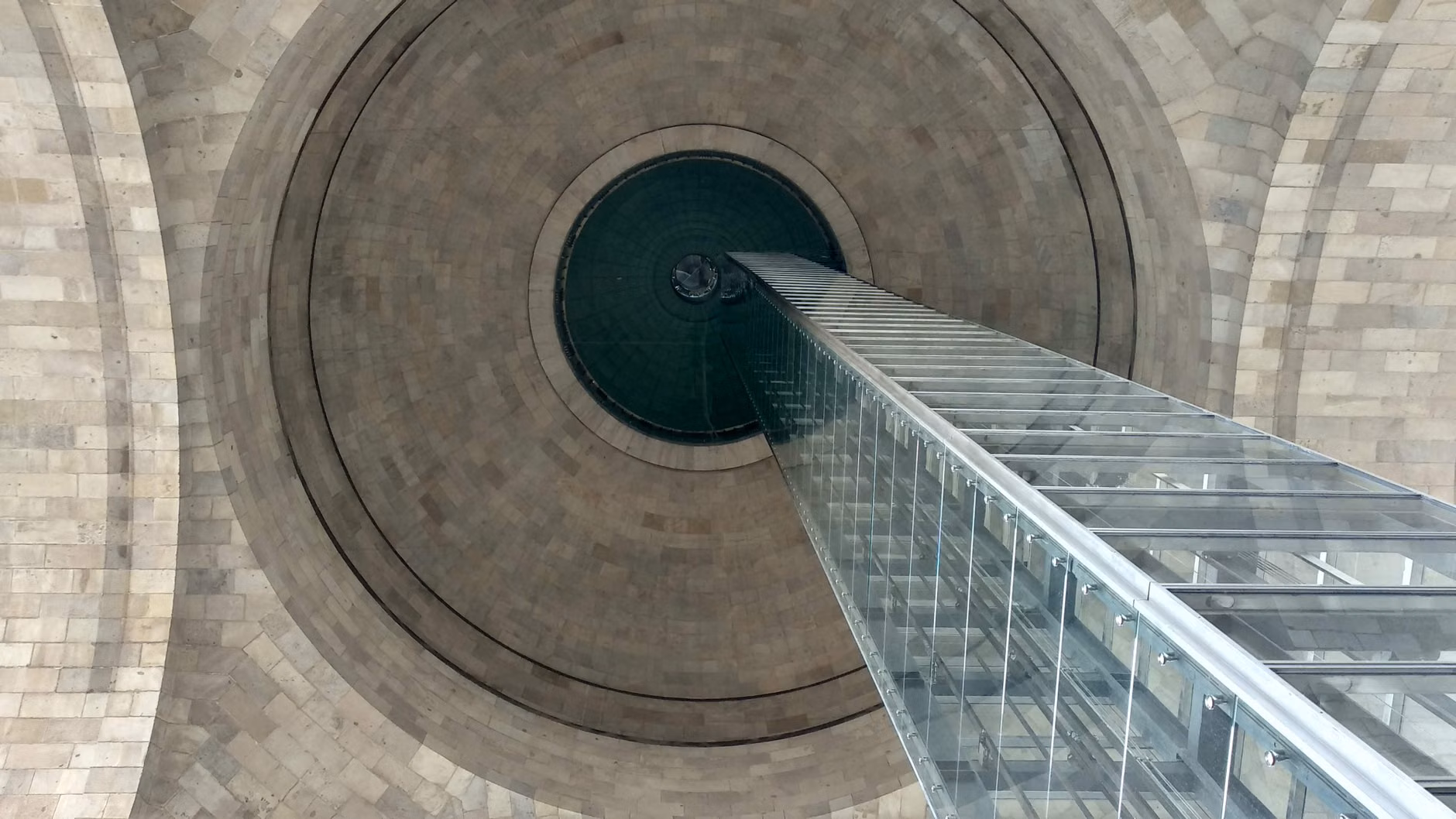 A modern glass elevator integrated into a historic stone building interior.
