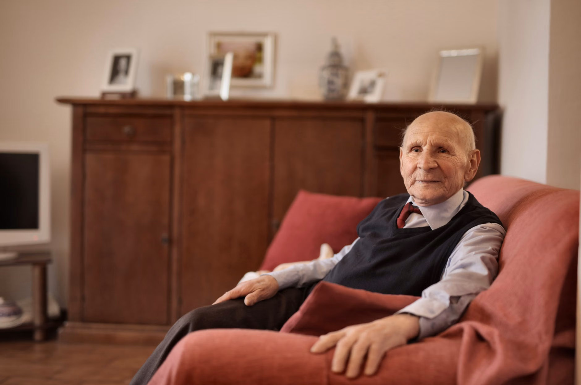 2026 Smart Home Energy Management: A Practical Guide for Independent Living 3 A senior person sitting comfortably in an armchair in a climate-controlled room, looking at a smart device.