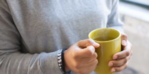 An older person holding a warm mug, representing the importance of grip strength for daily life.