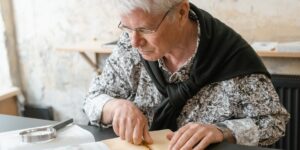 An elderly person researching genealogy with a magnifying glass and globe.
