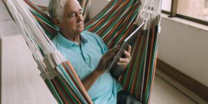 A senior person comfortably using a tablet in a well-lit home office.