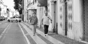 A senior couple walking through a historic European square with walking poles.