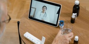 A senior couple using a tablet for a telehealth consultation on a European balcony.