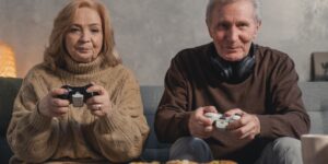 An older couple enjoying a video game together in a bright, comfortable living room.