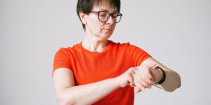 An elderly person looking at a smartwatch in a bright, modern living room.