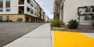 A modern, accessible city street designed for all ages, featuring wide sidewalks and green spaces.