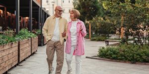 An active senior couple walking in a park, demonstrating good posture.