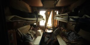 A modern and cozy European sleeper train cabin interior during sunset.
