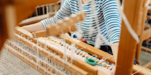 A peaceful home studio with a traditional wooden floor loom and colorful yarn.