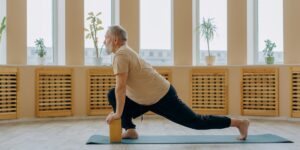An elderly person stretching comfortably in a sunlit room.