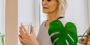 A senior person holding a glass of water in natural light.