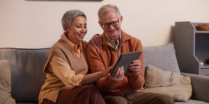 A senior couple using a tablet to communicate with a local at a cafe.