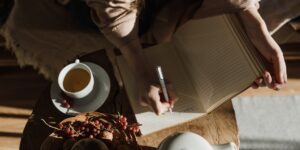An open recipe book and pen on a wooden table, representing the preservation of family culinary history.