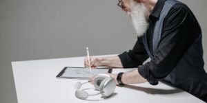 An elderly person enjoying digital sketching on a tablet in a comfortable home setting.
