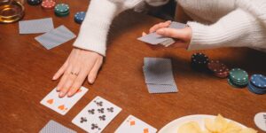 Two people playing cards at a wooden table in warm sunlight.
