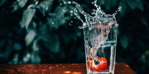 A refreshing glass of water and fruit on a wooden table representing senior health and hydration.