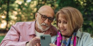 A senior couple using a smartphone for navigation on a scenic mountain trail.