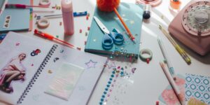 A cozy creative workspace featuring an open scrapbook, craft supplies, and a warm cup of tea.