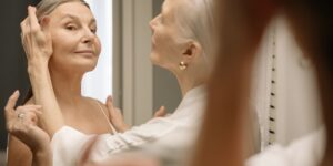 An elderly person applying a warm compress to their eyes for comfort.