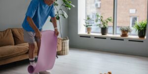 An elderly person performing a gentle calf stretch while holding onto a sturdy chair for support.