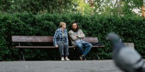 An older couple talking on a park bench, representing healthy social connection.