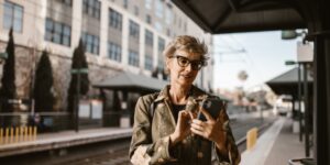 A senior traveler using a smartphone in a train station.