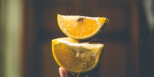 A senior person holding a slice of orange in sunlight, symbolizing healthy aging and nutrition.