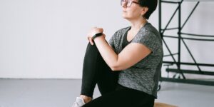 A senior person performing gentle seated knee exercises in a sunlit living room.