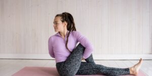 A senior woman performing a seated spinal twist in a sunny living room.