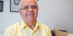 A happy senior individual smiling in a bright room, representing oral health and vitality.