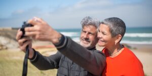A senior couple using a smartphone to navigate a scenic, quiet rural train station platform.