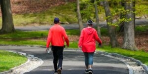 A senior couple walking on a paved, accessible forest trail.