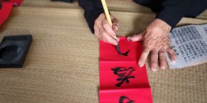 Close-up of elderly hands practicing traditional paper-folding on a wooden table.