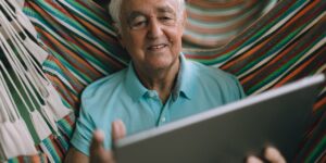 A senior person comfortably using a tablet to access digital services in a well-lit room.
