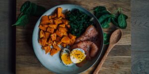 A selection of nutrient-dense foods including eggs, salmon, and vegetables on a wooden table.