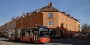 A modern electric shuttle bus in a sunny, historic European city square.
