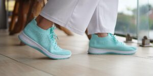 A modern, lightweight suitcase and comfortable walking shoes in a bright hotel room.