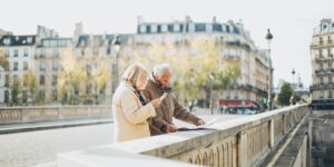 A senior couple reviewing a digital transit map at a modern train station.