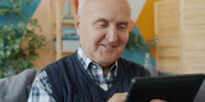An older adult using a digital health portal on a tablet at home.