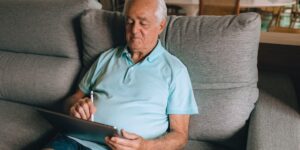 A senior adult using a tablet in a bright home office.