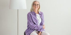 An active senior sitting with excellent posture in a bright, sunlit room.