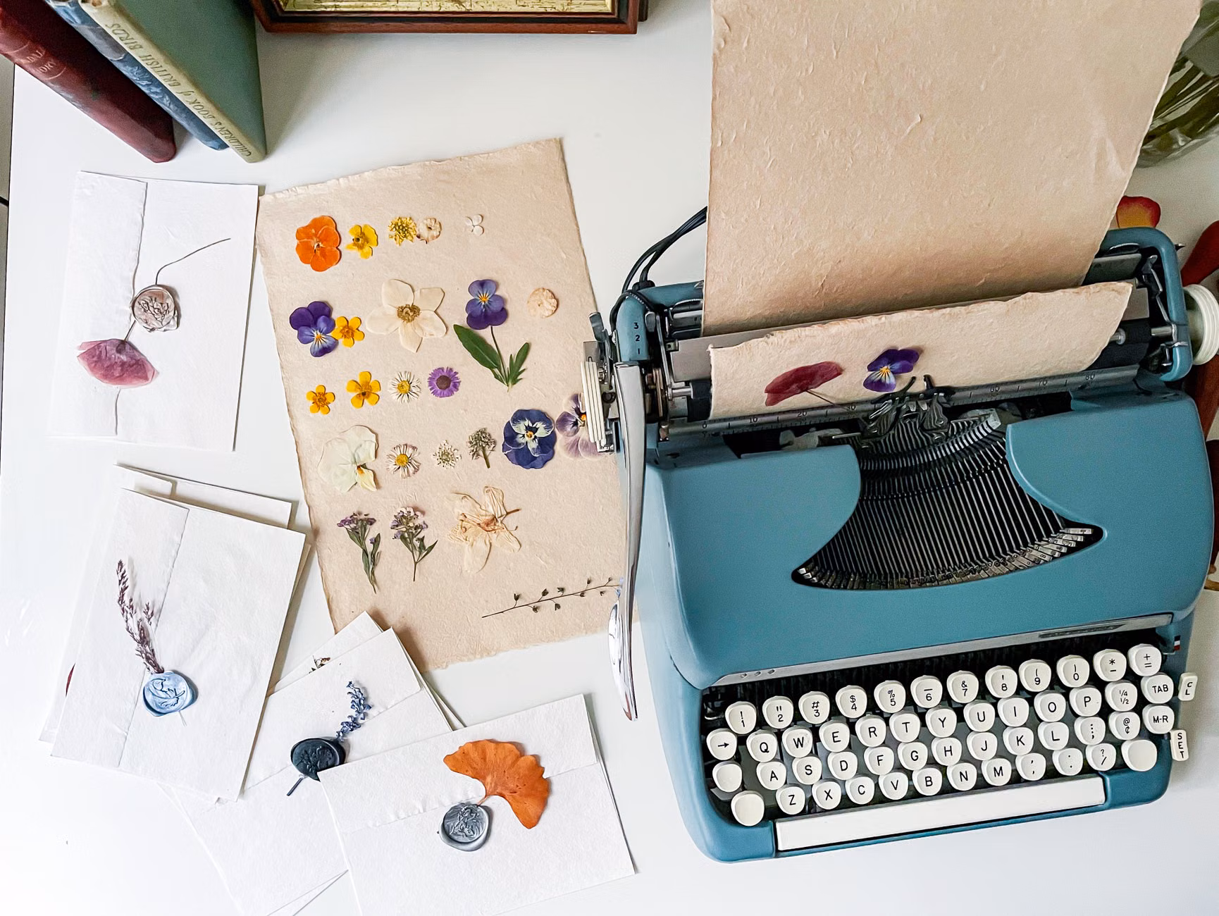 Hands using tweezers to place a pressed pansy on paper.