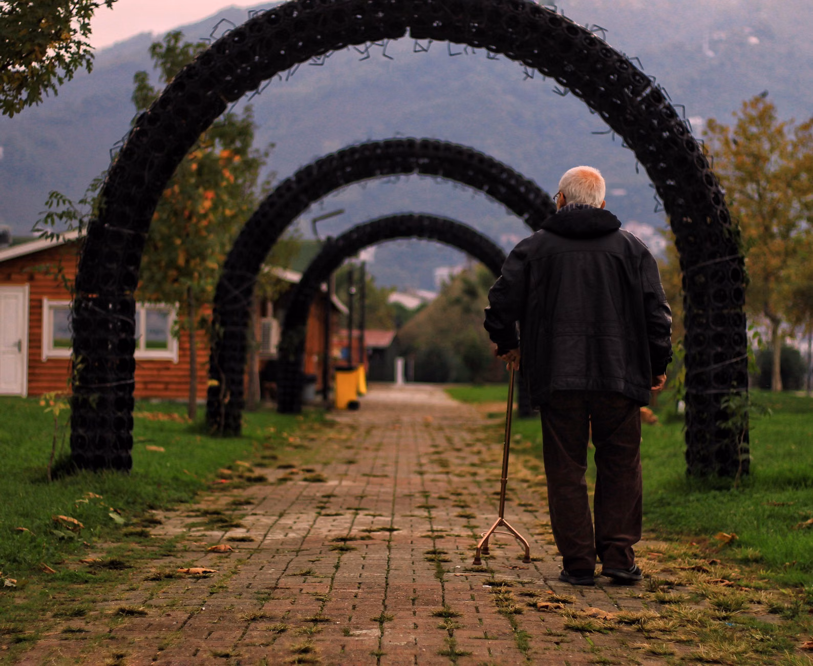 Senior traveller using a cane on a flat garden path.
